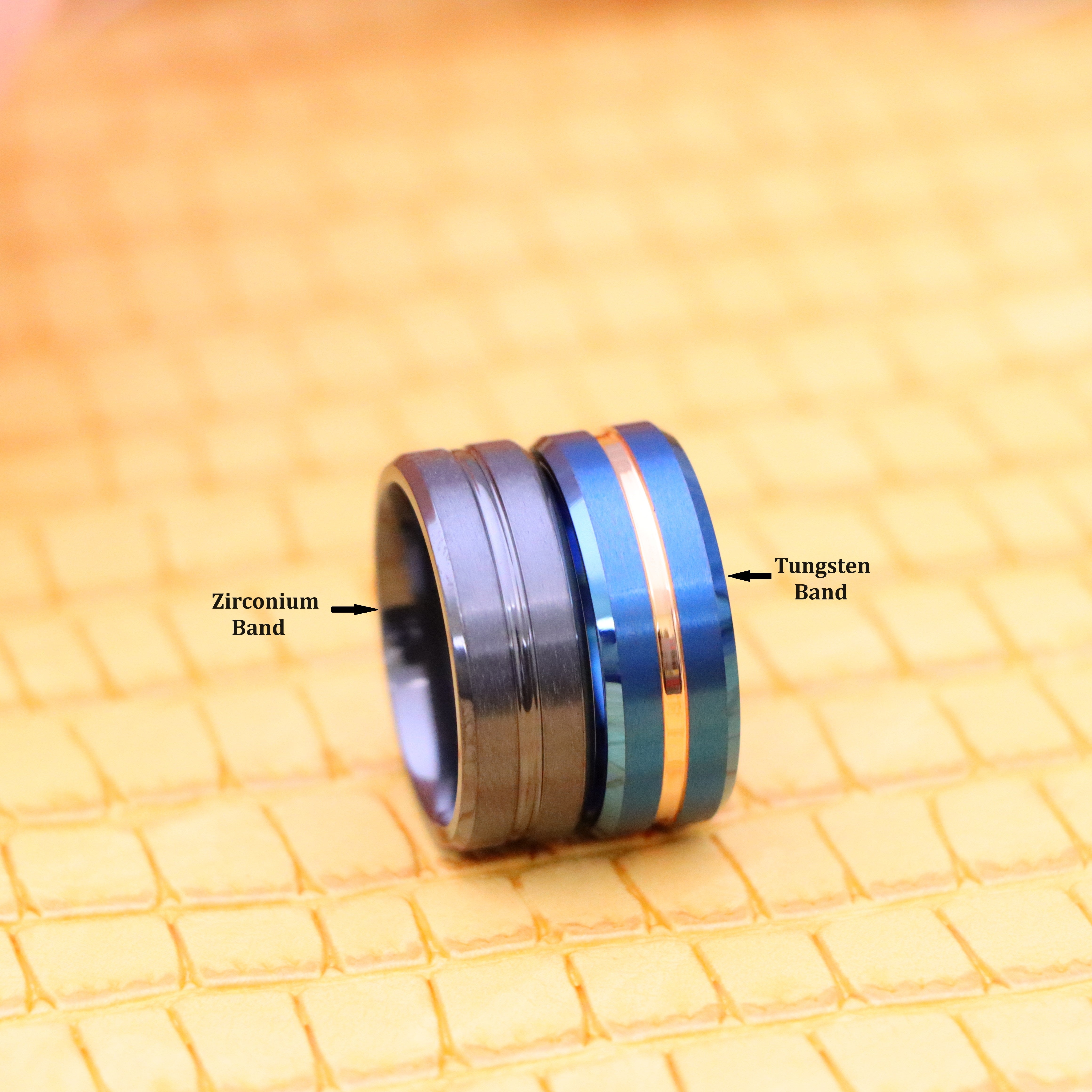 Two natural gun metal blue rings that includes one 8mm Zirconium band on the left side and one 8mm tungsten band with Rose Gold strip in center on the right side