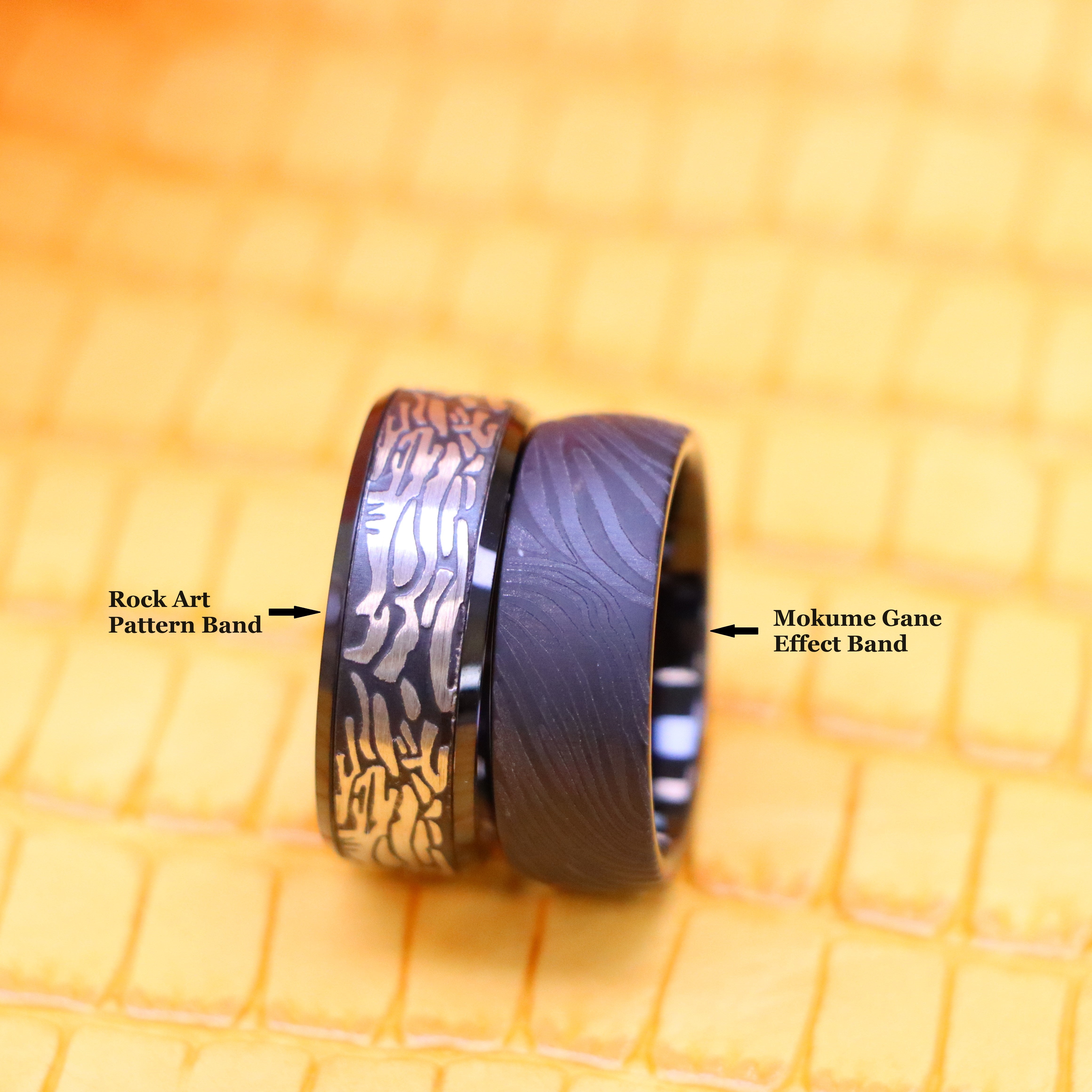 8mm Black IP Plated Semi-Dome Laser Carved Mokume Gane Effect (wood grain effect) Tungsten Ring and 8mm Black IP Plated Laser Carved Rock Art Pattern Tungsten Ring for bold men and women - clear front view with tags