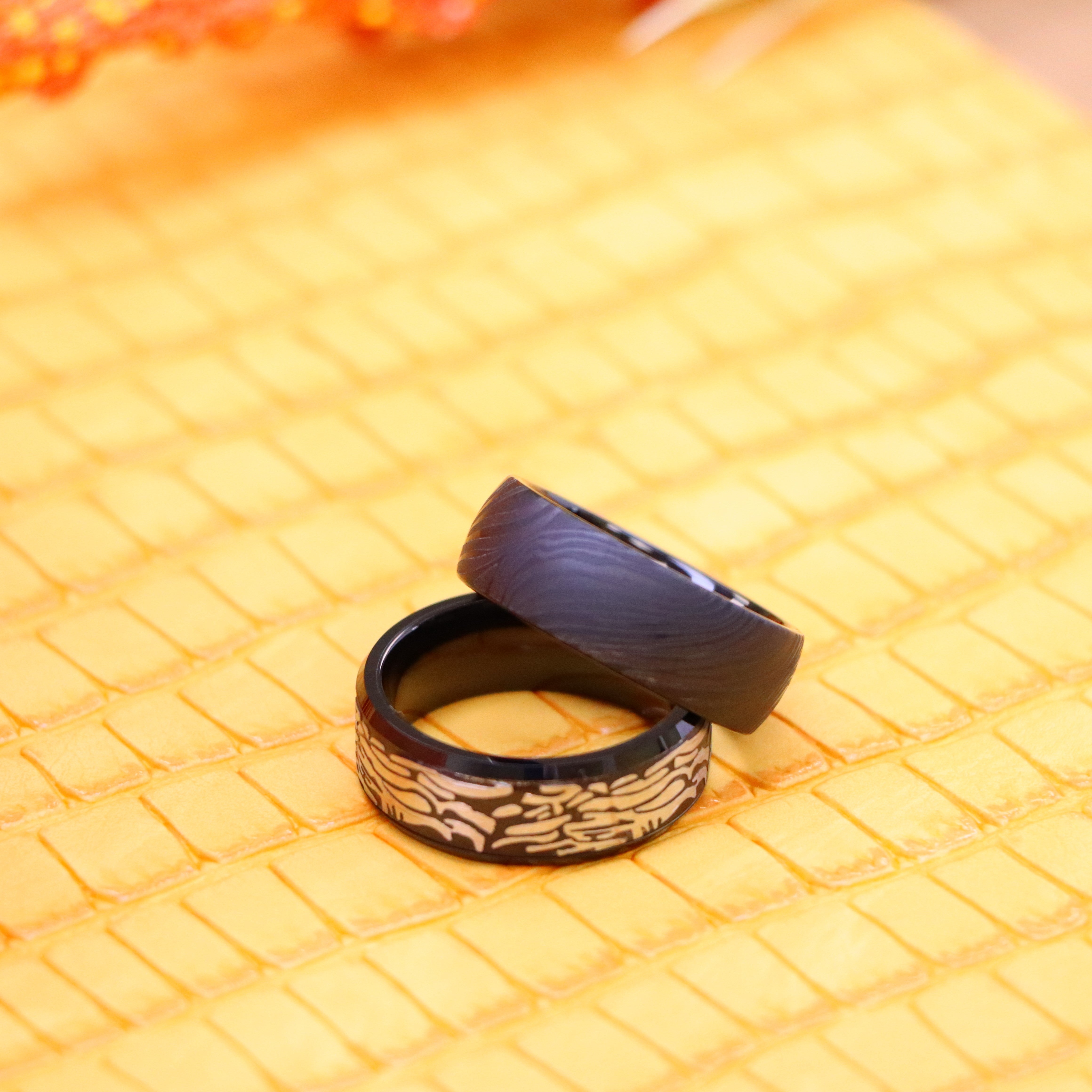 8mm Black IP Plated Semi-Dome Laser Carved Mokume Gane Effect (wood grain effect) Tungsten Ring and 8mm Black IP Plated Laser Carved Rock Art Pattern Tungsten Ring for bold men and women - one on one view