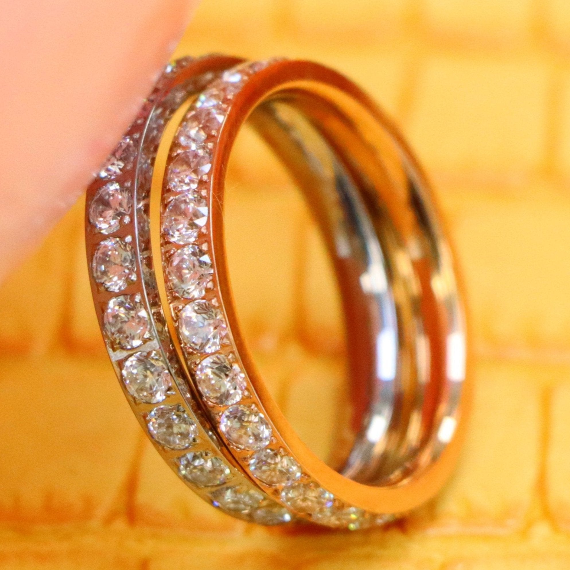 3mm White and Rose Gold Full Eternity White CZ titanium rings supported with a finger from left side