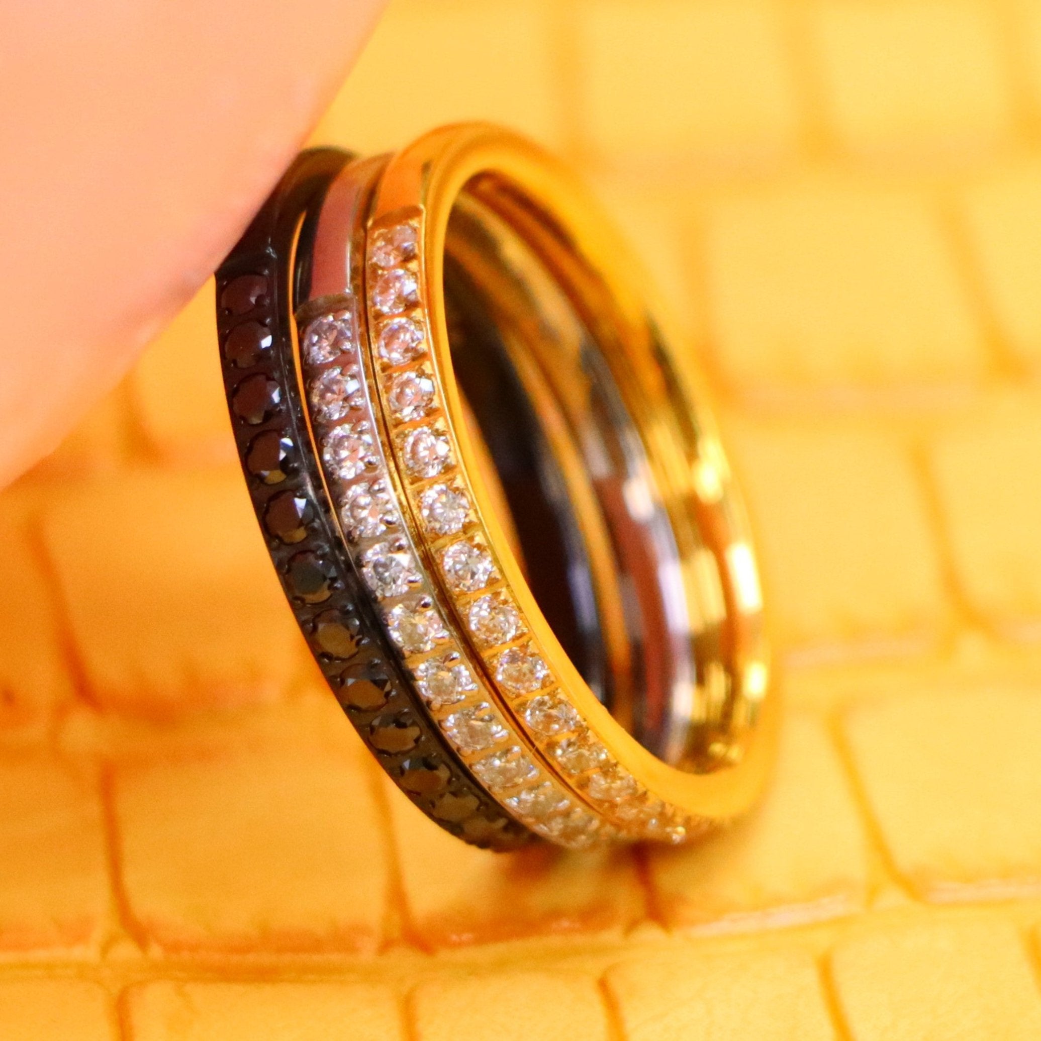 2mm Yellow, Black, Silver Titanium Half Eternity Titanium Ring with White cz stones on yellow and silver titanium rings and black CZ Stones on black titanium ring supported with a finger from left side