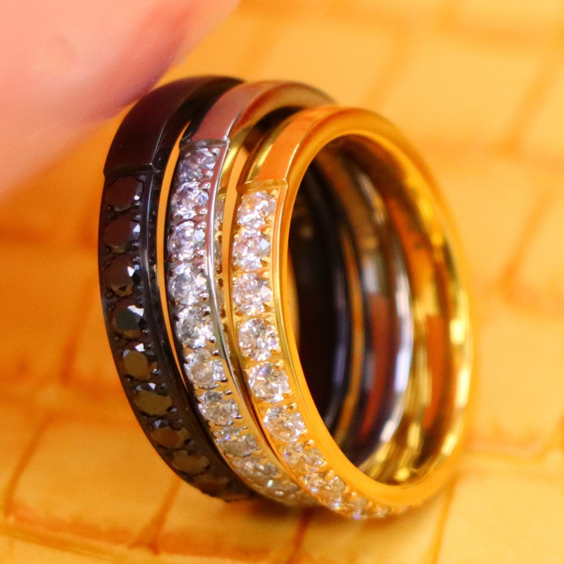 3mm Titanium and yellow IP Plated Half Eternity black CZ ring and 3mm black IP Plated Half Eternity black CZ ring supported with a finger from left side